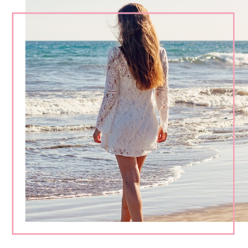 A woman in white dress walking on a beach